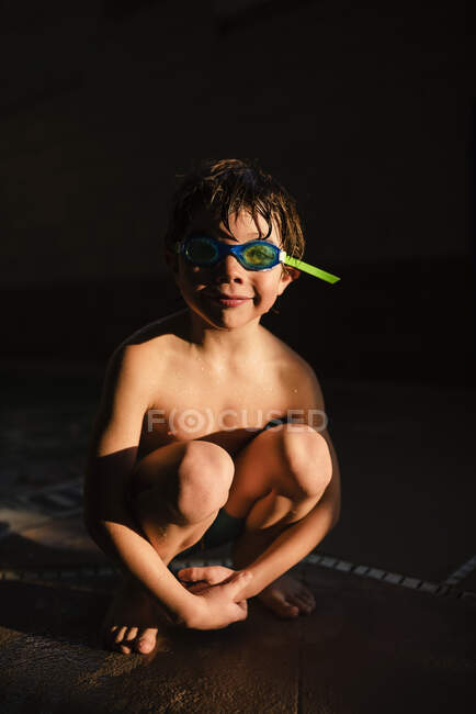 Retrato de niño con gafas bajo el agua sentado a la luz del sol - foto de stock