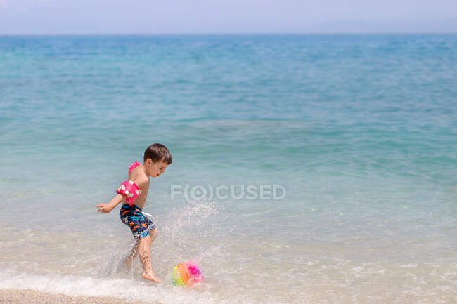 Chico pateando una pelota en la playa, Grecia - foto de stock