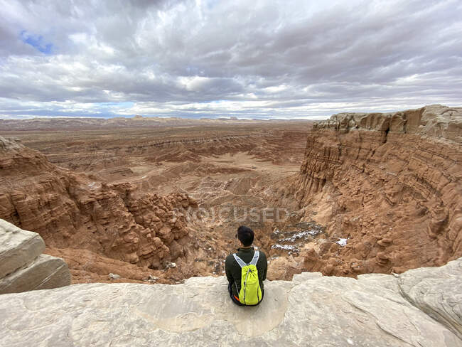 Rear view of a man sitting on cliff edge, Goblin Valley State Park, Utah, USA — Stock Photo