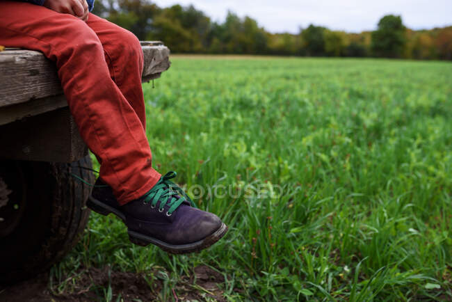 Close-up of a boy's legs sitting on a wagon — Stock Photo