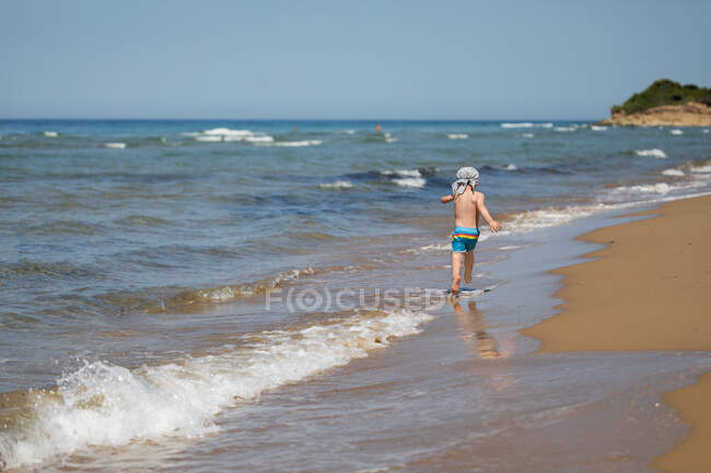 Мальчик бегает по пляжу, Корфу, Греция — стоковое фото