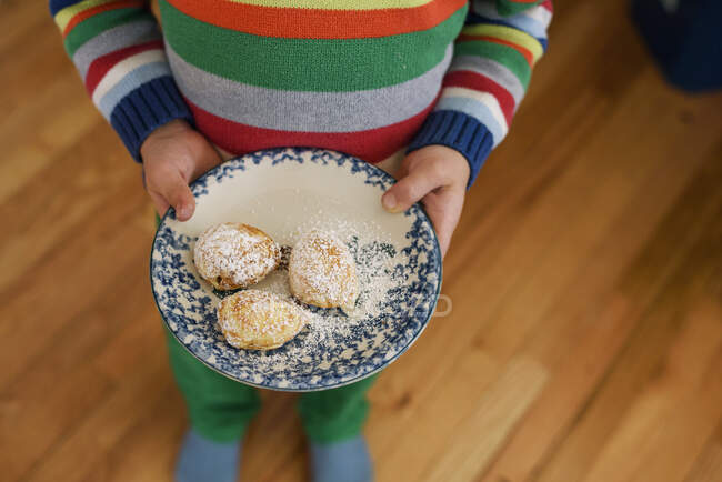 Вид зверху хлопчика, що тримає тарілку з пончиками — стокове фото