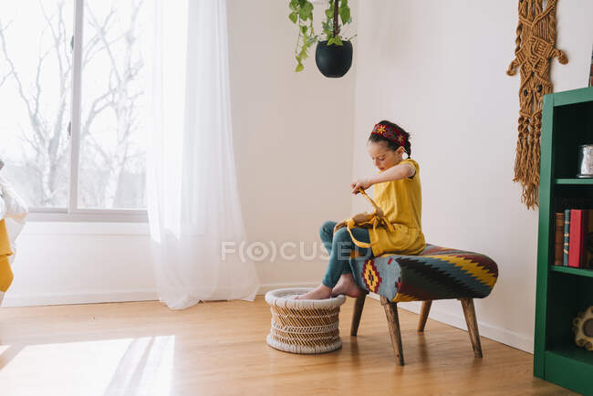 Дівчина сидить на табуреті, закриваючи рюкзак — стокове фото