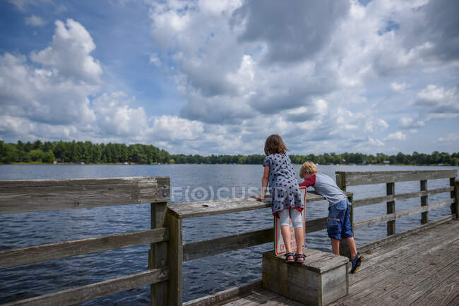 Boy and girl standing on a dock fishing in summer, United States — Stock Photo