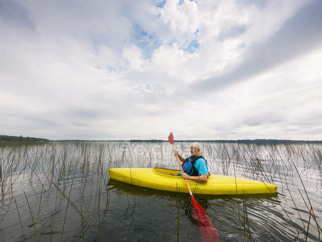 Старшая женщина на байдарках на озере, США — стоковое фото