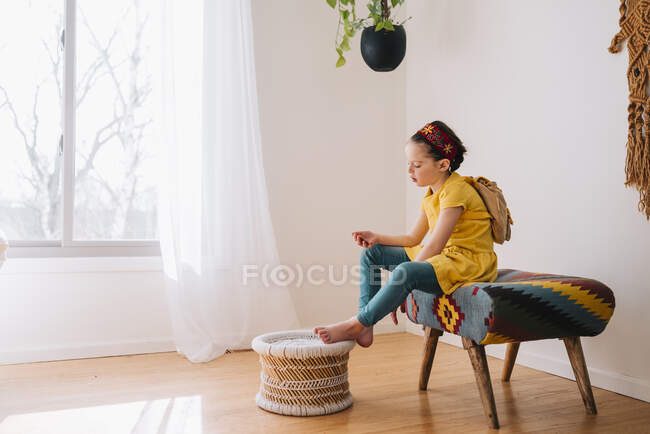 Chica sentada en un taburete mirando un pedazo de papel - foto de stock