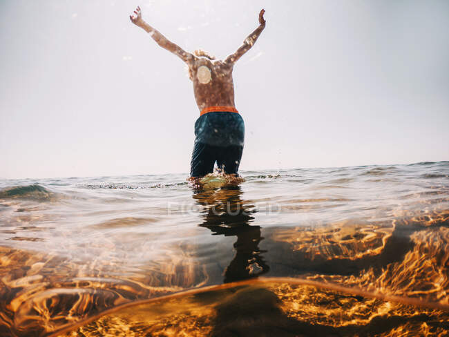 Boy standing in a lake with his arms raised, Lake Superior, United States — Stock Photo