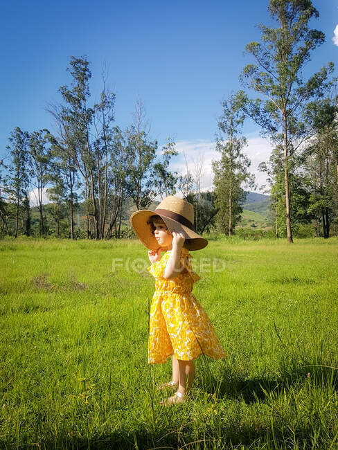 Girl standing in a field wearing a summer hat, Brazil — Stock Photo