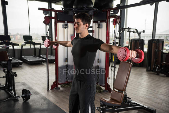 Mann steht in Turnhalle und stemmt Gewichte — Stockfoto