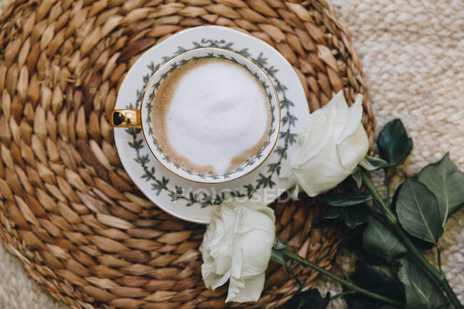 Xícara de café e rosas brancas em uma mesa — Fotografia de Stock