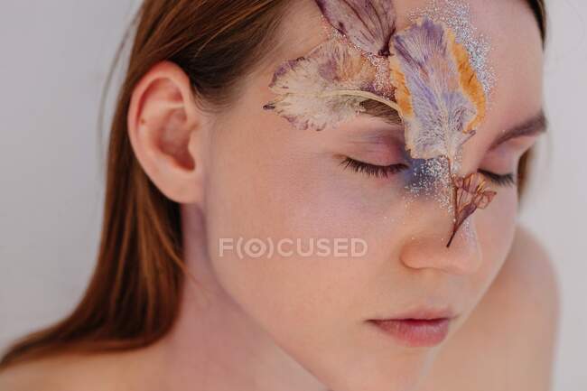 Konzeptionelles Schönheitsporträt einer Frau mit getrockneten Blumen im Gesicht — Stockfoto