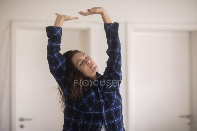 Woman standing in the living room stretching — Stock Photo