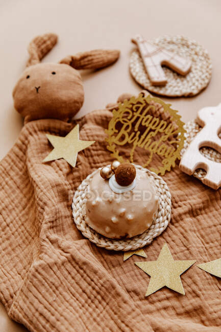 Close-up of a chocolate birthday cake surrounded by baby's toys and accessories — Stock Photo