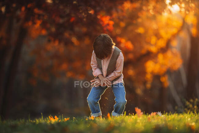 Boy standing outdoors brushing grass off his trousers, United Kingdom — Stock Photo