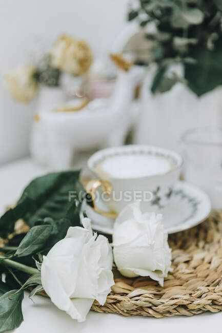 Xícara de café e rosas brancas em uma mesa — Fotografia de Stock