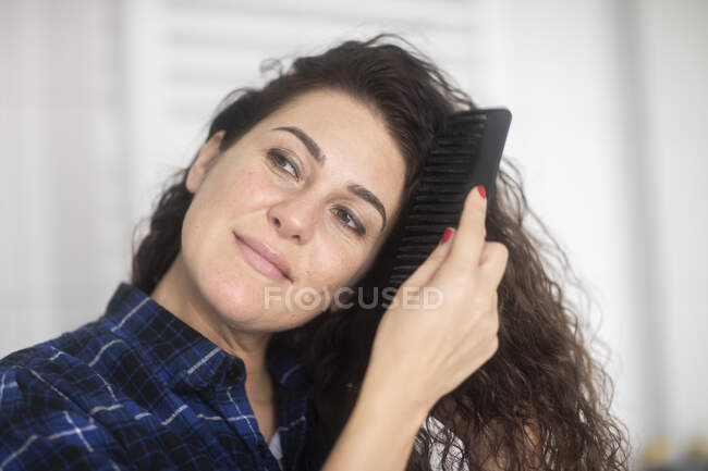 Mulher de pé no banheiro pentear o cabelo — Fotografia de Stock