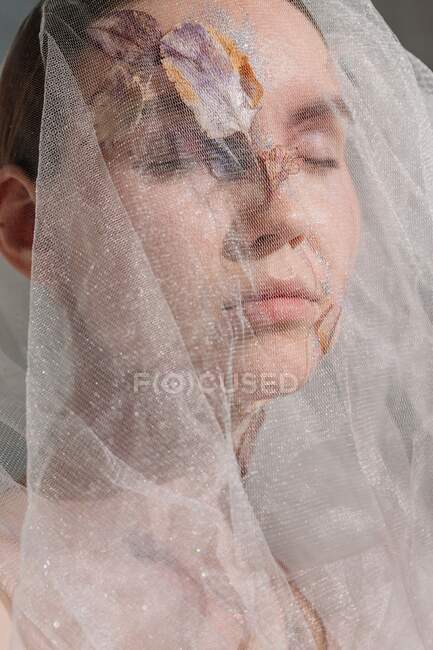 Conceptual beauty portrait of a woman wearing a veil with dried flowers on her face and neck — Stock Photo