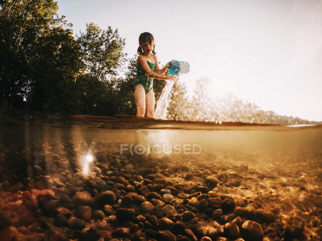 Mädchen steht in einem See und leert einen Eimer Wasser, Lake Superior, Vereinigte Staaten — Stockfoto