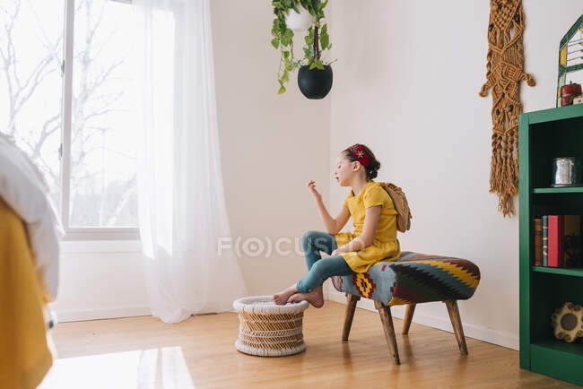Дівчинка сидить на стільці і дивиться на золотого ваучера. — стокове фото
