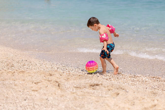 Хлопчик штовхає м'яч на пляжі, Греція. — стокове фото
