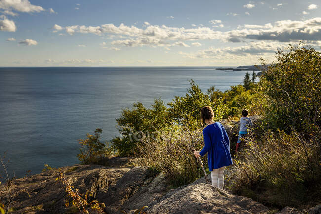 Boy and girl hiking across rocks by a lake, Lake Superior Provincial Park, United States — Stock Photo