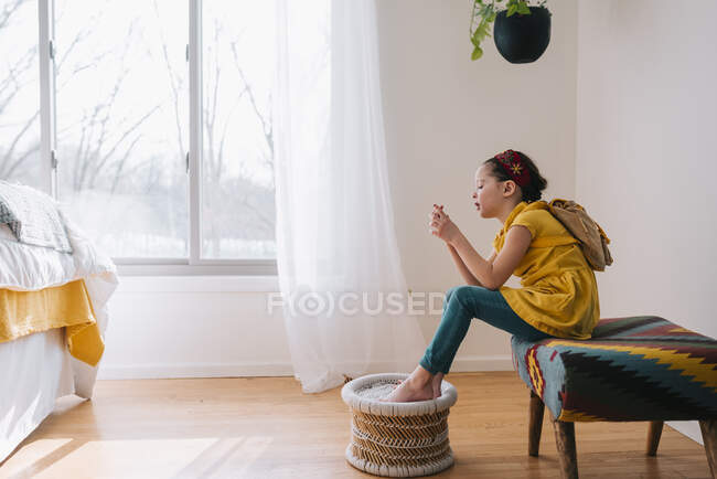 Mädchen sitzt auf einem Schemel und betrachtet ein Blatt Papier — Stockfoto