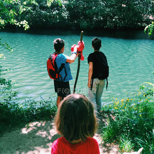 Tres niños caminando por un río en el verano, España - foto de stock