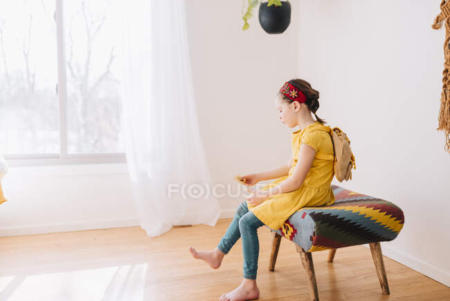 Retrato de uma menina sentada em um banquinho segurando um certificado de presente de ouro — Fotografia de Stock