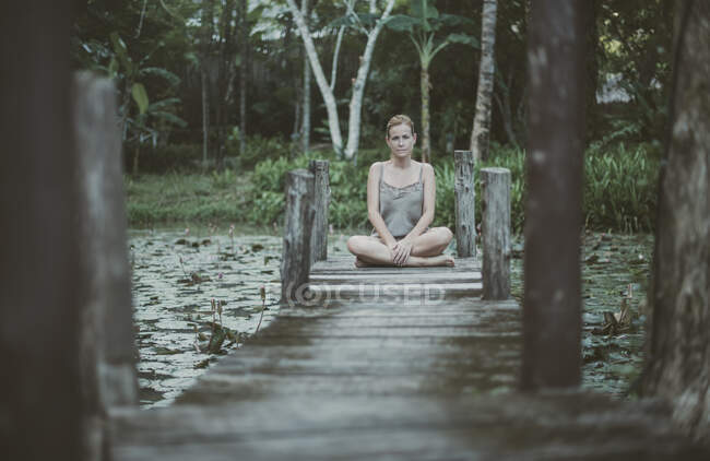 Mujer sentada con las piernas cruzadas en un embarcadero de madera, Koh Yao, Phang Nga, Tailandia - foto de stock