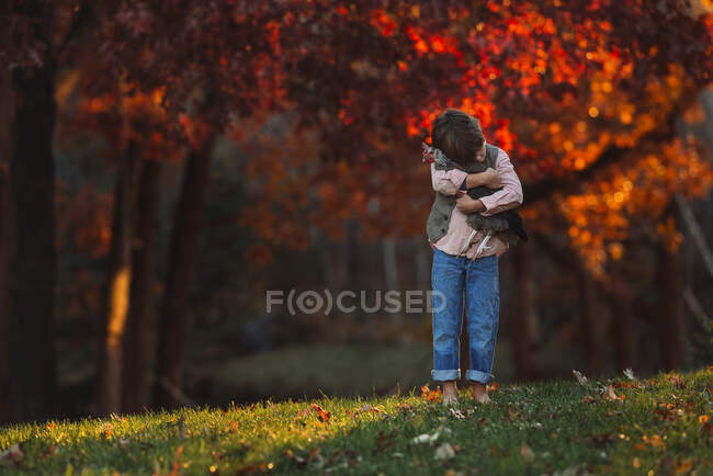 Boy standing outdoors cuddling a chicken, United States — Stock Photo