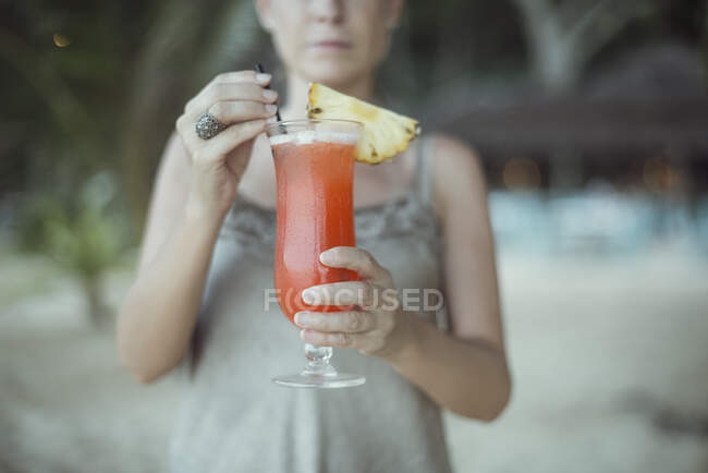 Mujer parada en la playa sosteniendo un cóctel tropical, Koh Yao, Phang Nga, Tailandia - foto de stock