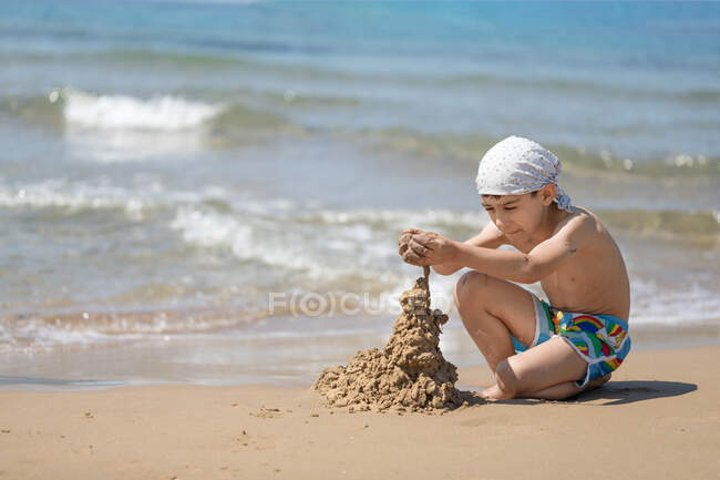 Garçon construisant un château de sable sur la plage, Corfou, Grèce — Photo de stock
