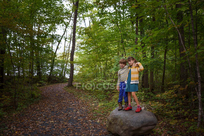 Garçon et fille debout sur un rocher dans la forêt au début de l'automne, États-Unis — Photo de stock