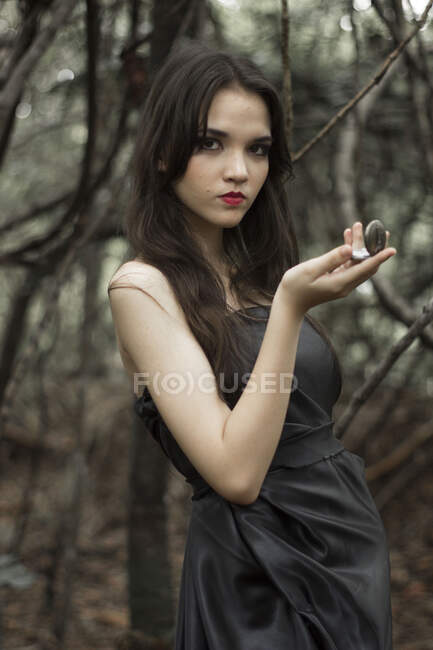 Portrait of a girl standing in the forest looking at a locket, United States — Stock Photo