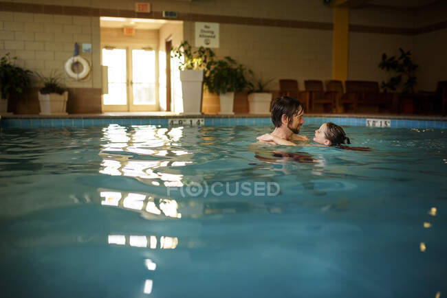 Padre sosteniendo a su hija en una piscina - foto de stock