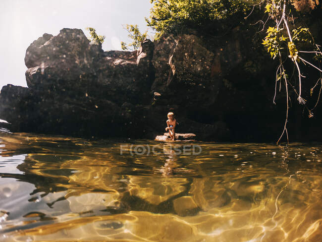 Мальчик-кузнец, стоящий на скале, озеро Саффолк, США — стоковое фото