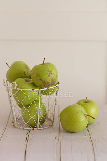 Свежие зеленые яблоки в металлической корзине на деревянном столе — стоковое фото