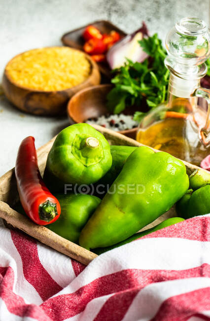 Arroz, chile, pimientos, aceite de oliva y condimentos en una mesa de cocina - foto de stock