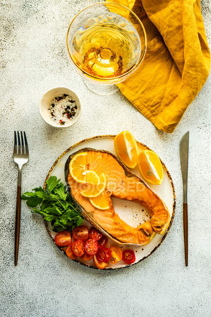 Bife de salmão grelhado com tomate, limão e um copo de vinho branco — Fotografia de Stock