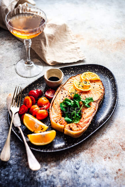 Bistecca di salmone alla griglia con pomodori, limone e un bicchiere di vino bianco — Foto stock