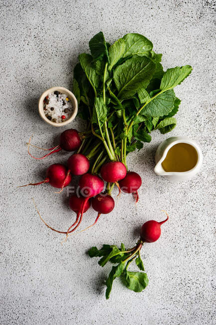 Ravanelli biologici freschi con olio d'oliva, sale e pepe su un tavolo — Foto stock