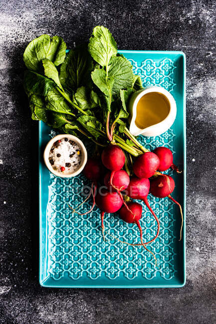 Plate of fresh organic radishes with olive oil, salt and pepper — Stock Photo