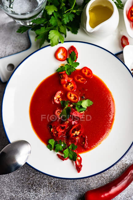 Вид сверху на тарелку томатного супа со свежим чили и петрушкой — стоковое фото