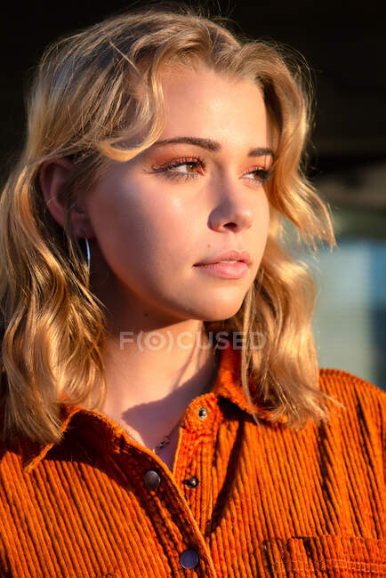 Portrait of a beautiful woman standing in garden with sunlight on her face — Stock Photo