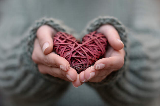 Primo piano delle mani di una donna che tiene una decorazione a forma di cuore — Foto stock