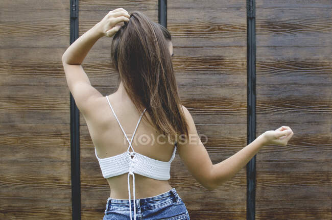 Rear view of a teenage girl standing outdoors touching her hair — Stock Photo