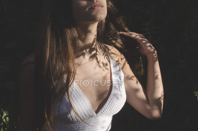 Close-up of a teenage girl standing in the garden summer sunlight touching her hair — Stock Photo