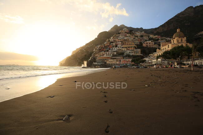 Coucher de soleil, plage de sable et vieux bâtiments éloignés sur la colline — Photo de stock