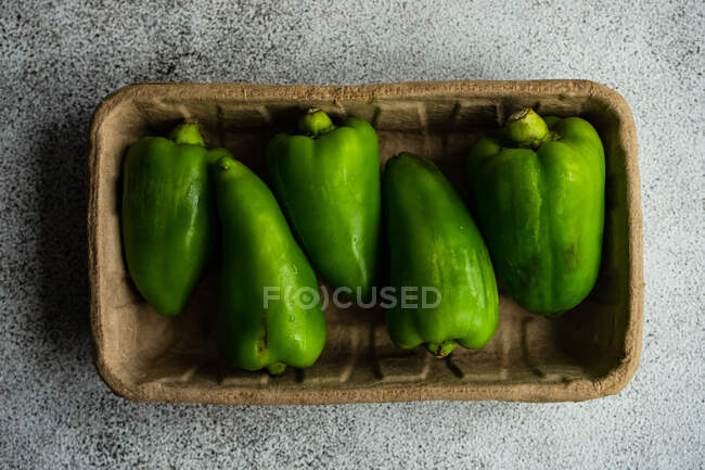 Overhead view of fresh green bell peppers in a cardboard box — Stock Photo