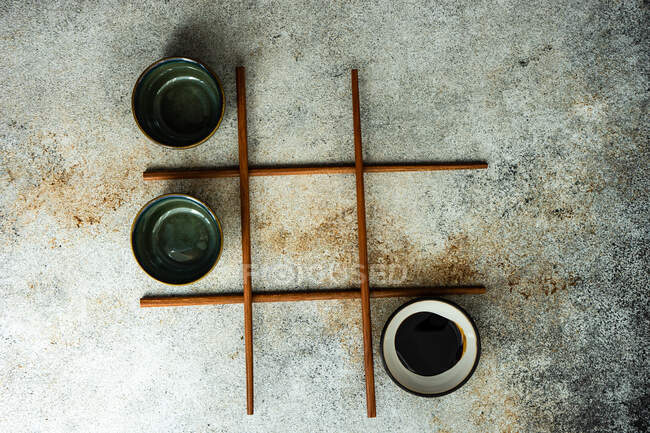 Вид сверху на игру в ноли и кресты с использованием азиатских палочек для еды и миски — стоковое фото